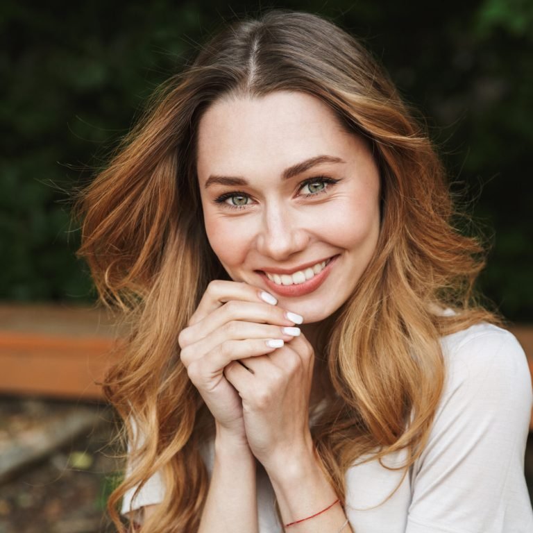 Close up of a smiling young girl looking at camera while sitting outdoors