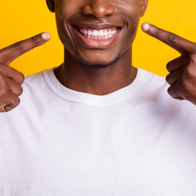 Cropped view portrait of attractive cheerful guy demonstrating white teeth isolated over vibrant yellow color background.