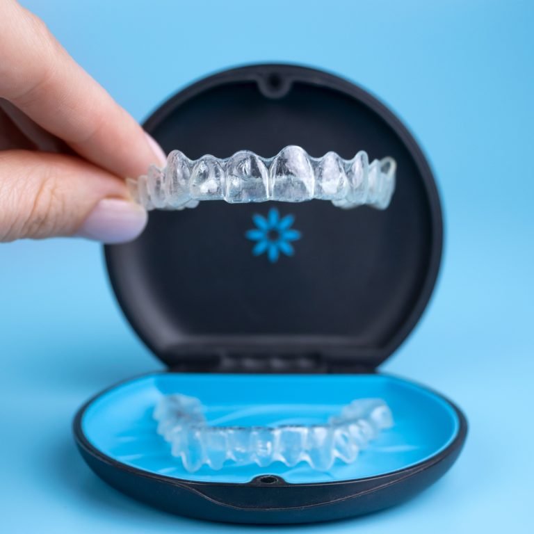 Woman holding invisalign transparent retainers with a box on the table, flatlay top view. Selective focus.